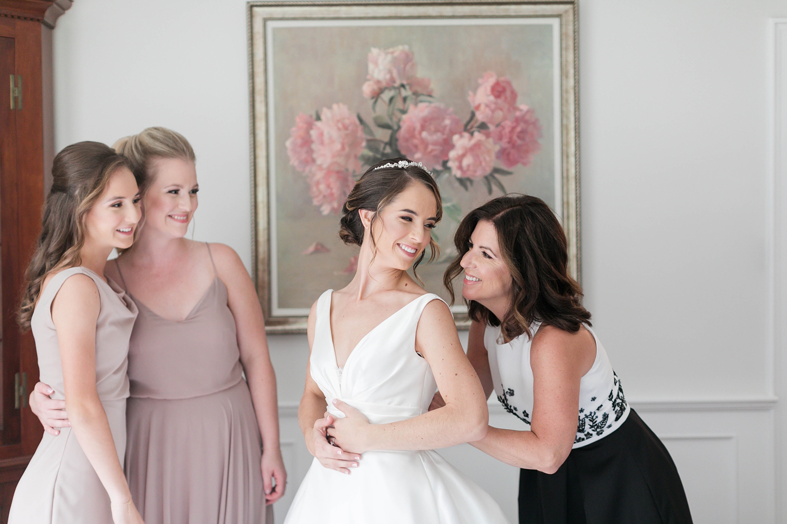 mom and daughters help their daughter and sister get ready on wedding day