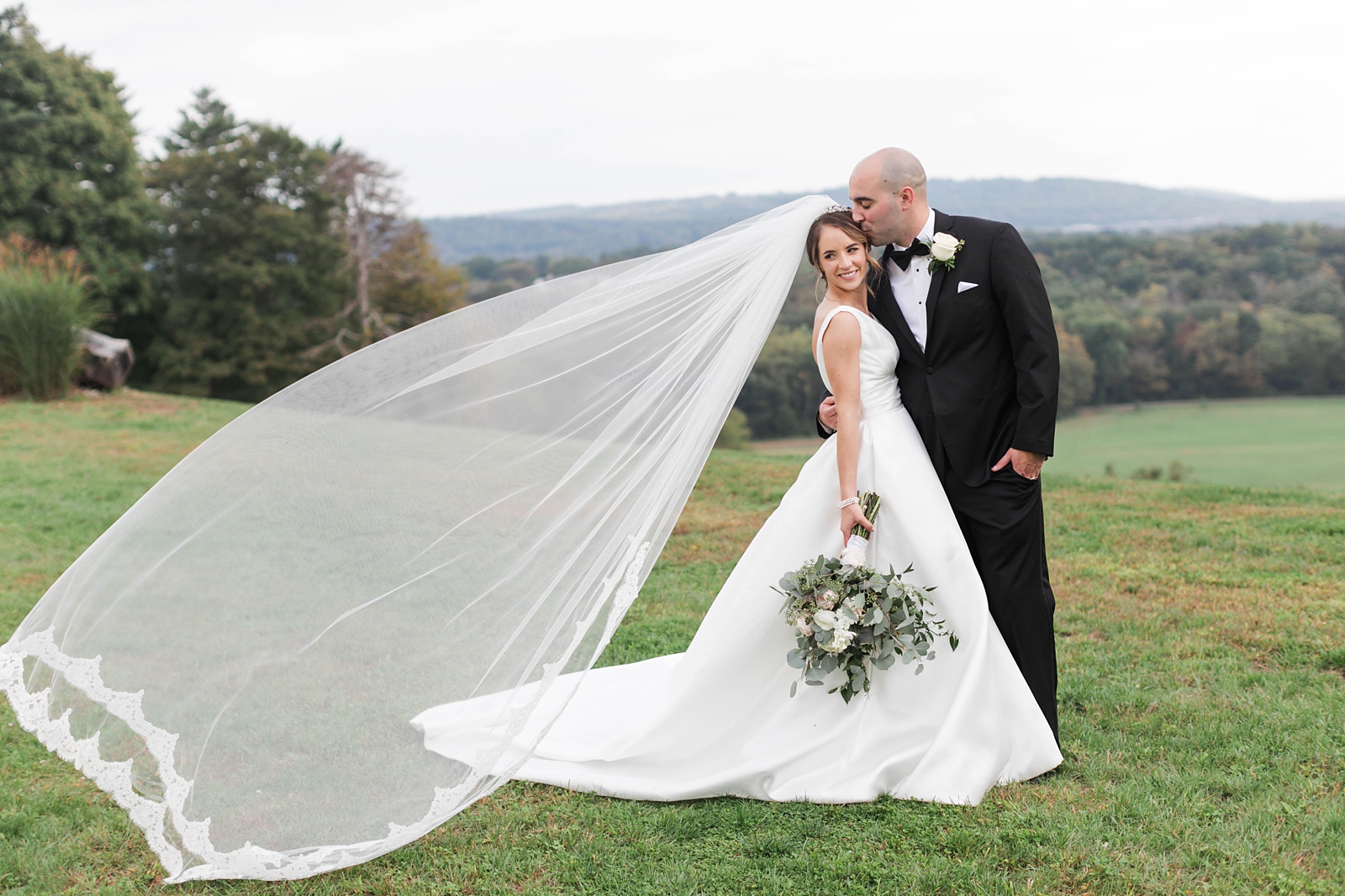 brides veil blowing in the wind with husband in front of the rolling mountain hills at The Mansion at Natirar Wedding