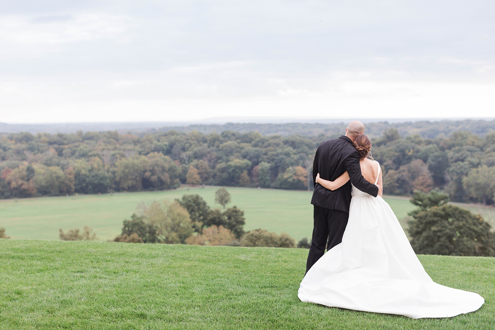 bride and groom hold each other as they look over the greenery mountains at The Mansion at Natirar Wedding