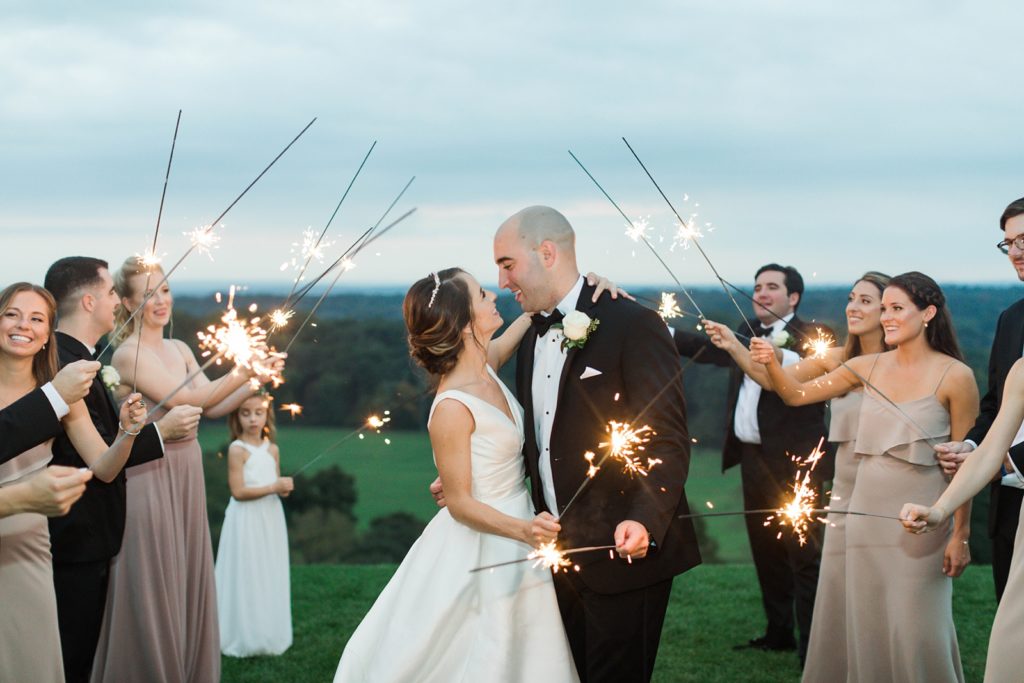 bride and groom leave wedding reception by a sparkler exit in front of the mountains