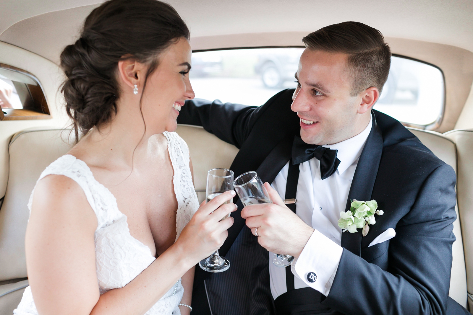 bride and groom cheers champagne in antique car after saying i do at their Newark, NJ wedding