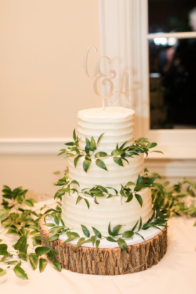 classic tripe layer white wedding cake with greenery around it