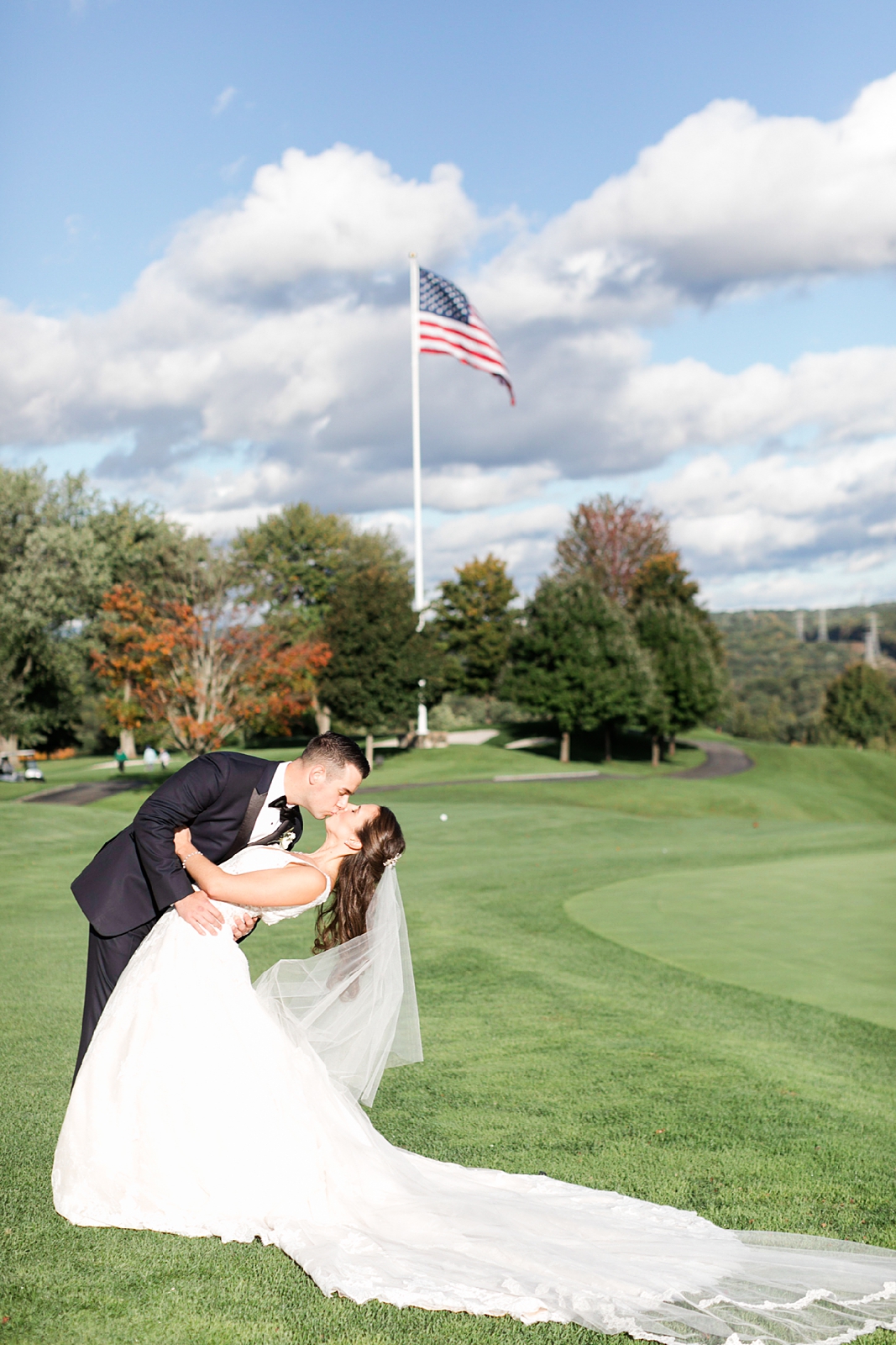 Trump National Golf Club Westchester Wedding groom dipping bide and kissing in front of the American Flag