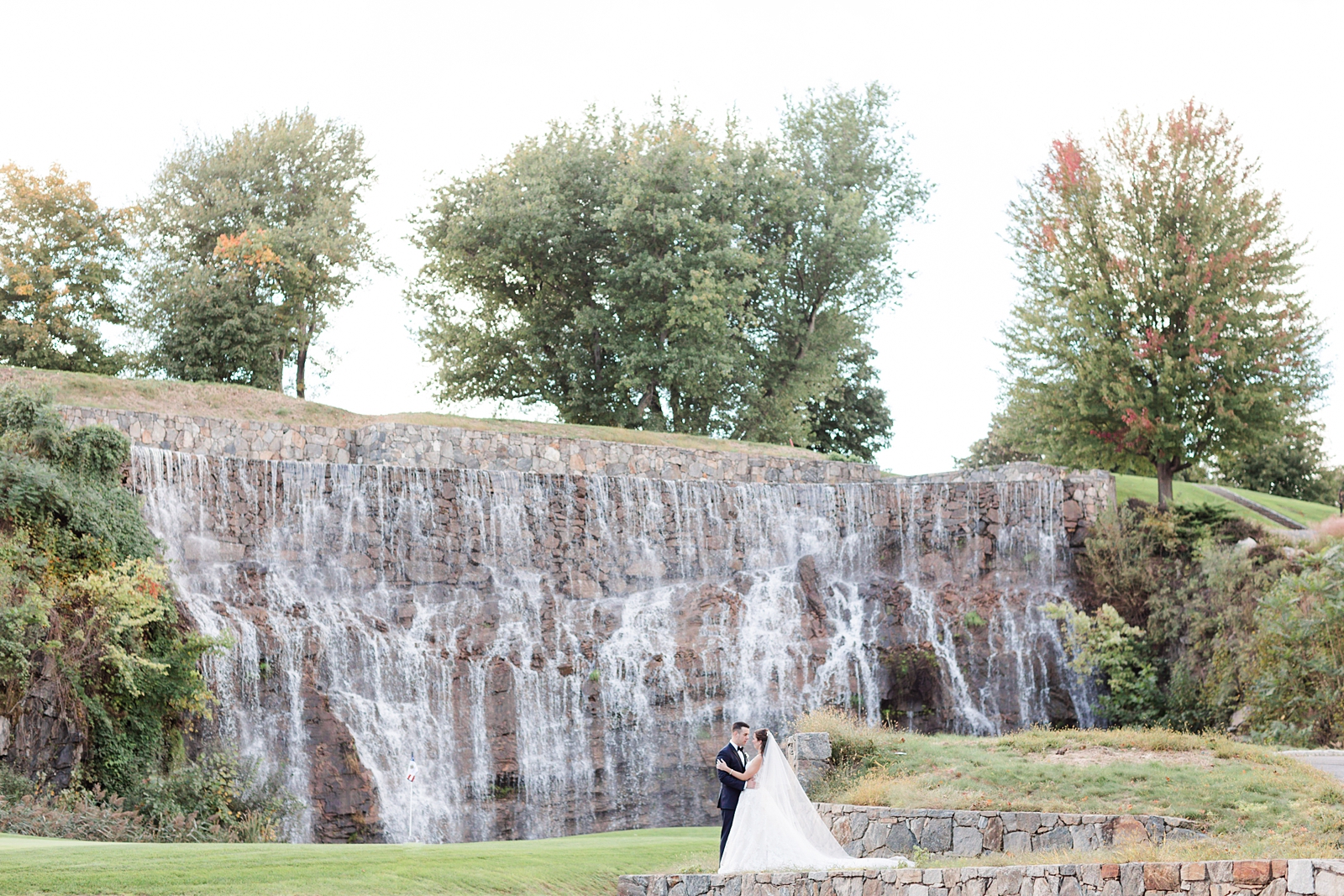 bride and groom take bridal portraits in front of the big waterfalls at Trump National Golf Club Westchester