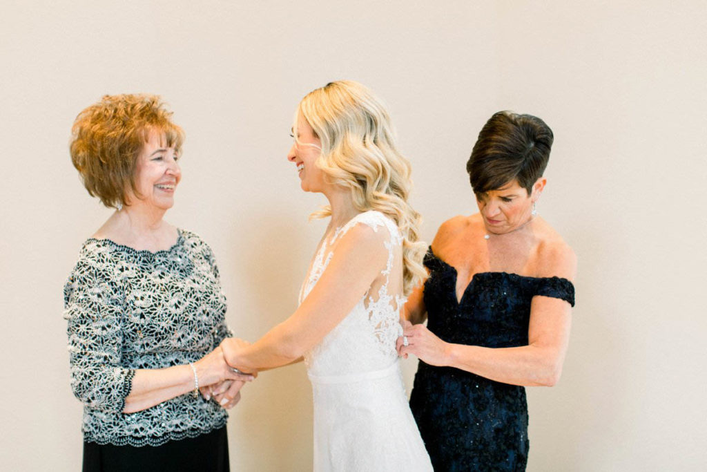 grandmother and bride help bride into the dress