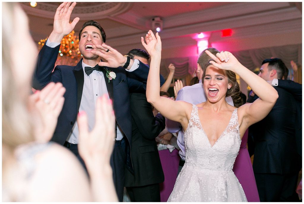 bride and groom celebrating their marriage by dancing on the dance floor with guests from reception