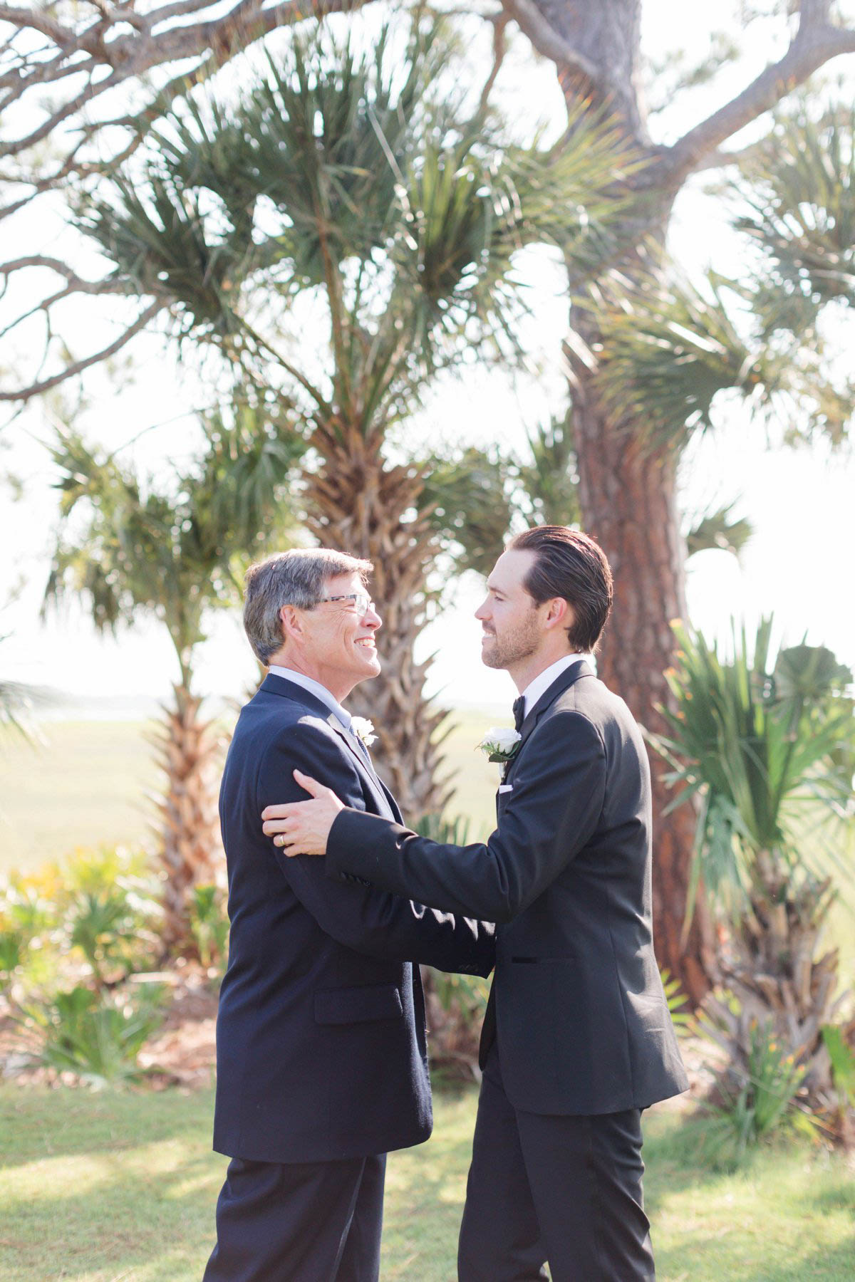Groom and Father of Groom exchange hug before seeing bride down the island