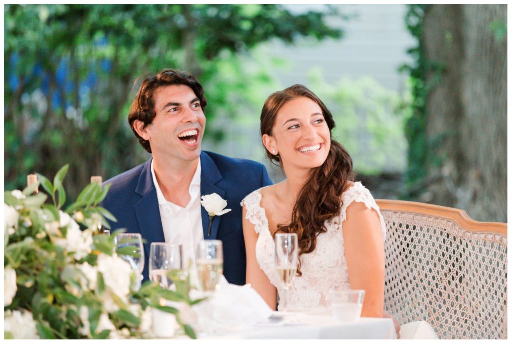 Bride and groom laugh during toasts at backyard wedding day
